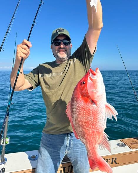 Freshly caught red snapper displayed on fishing boat deck with fishing rods