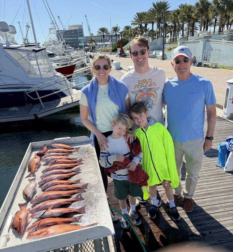 Fresh caught red snapper fish displayed on cleaning table at marina dock with boats in background