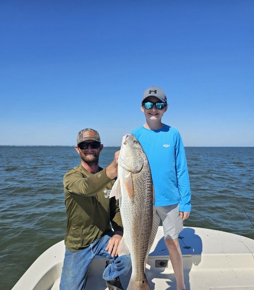 Redfish catch displayed on boat deck with ocean water in background
