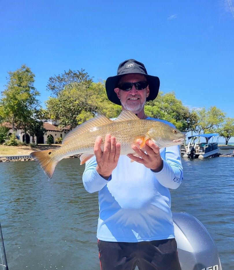 Angler holding freshly caught redfish on boat in calm waters