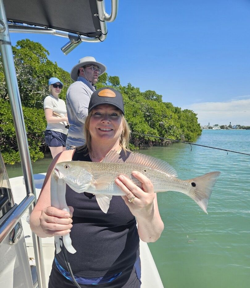 Successful redfish catch displayed on fishing boat with mangroves and clear water in background