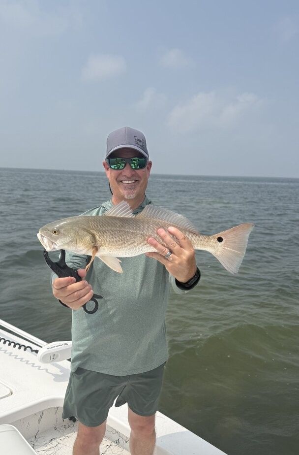Redfish being held on fishing boat with ocean water in background
