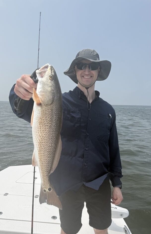 Angler holding freshly caught redfish on fishing boat in open water