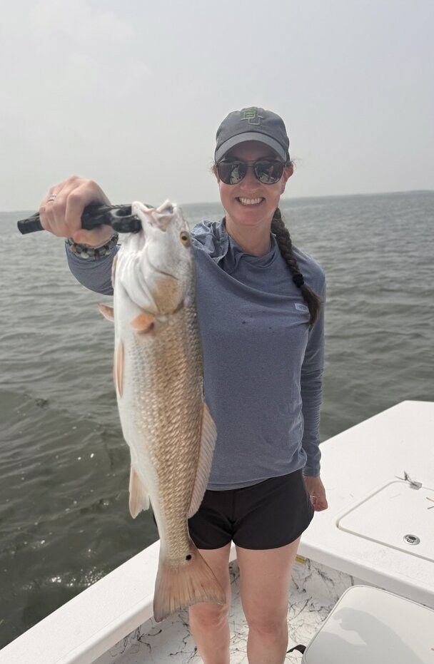 Freshly caught redfish being held up on fishing boat over open water