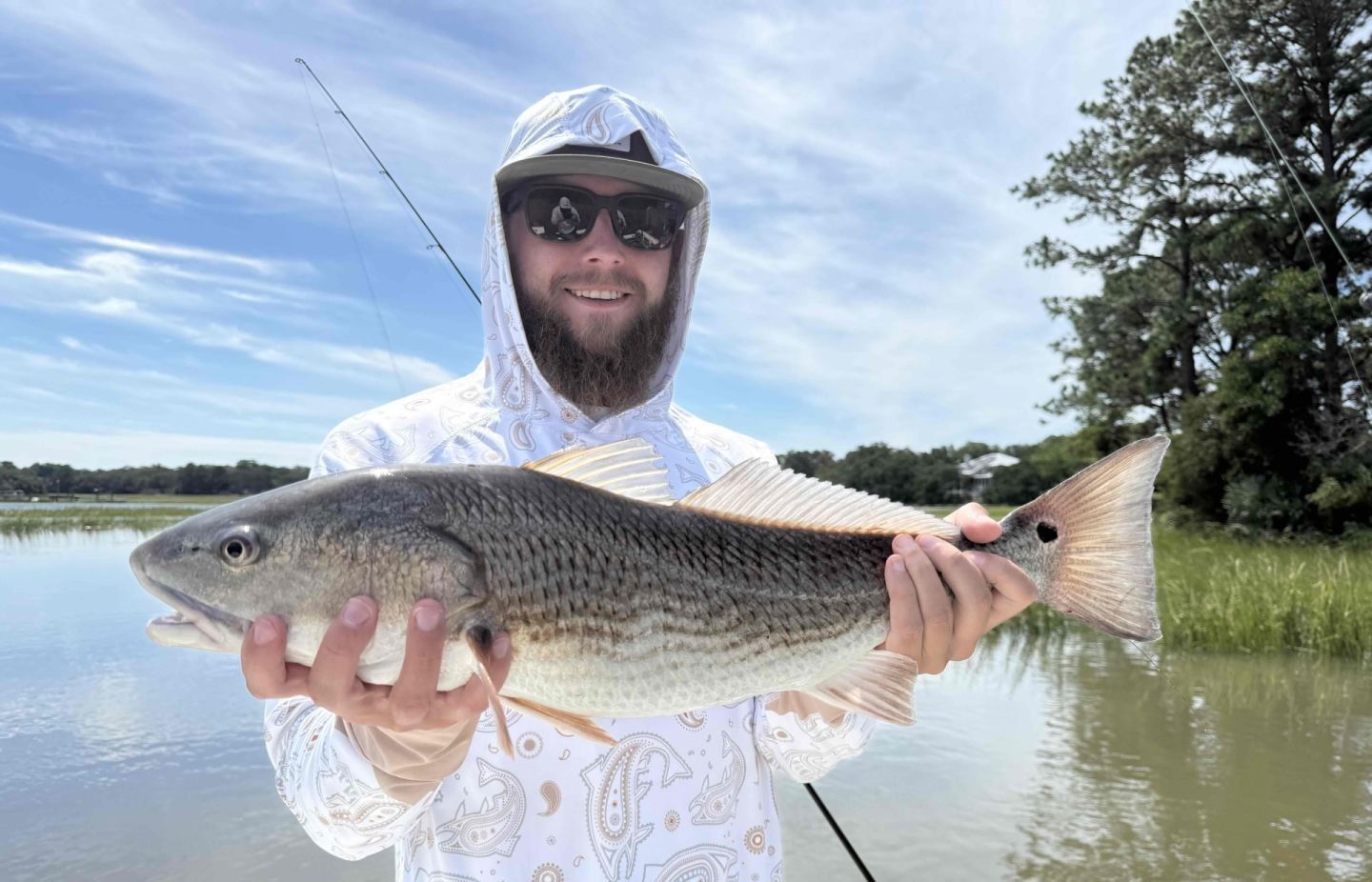 Angler holding caught redfish while fishing in shallow water