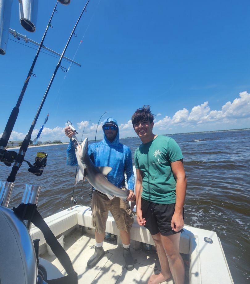 Fishing charter boat with caught shark being displayed on deck in open water