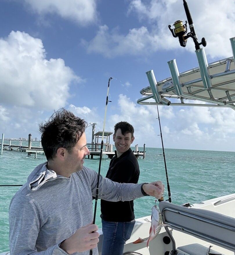 Fishing rod with small fish catch on boat deck with ocean and dock in background
