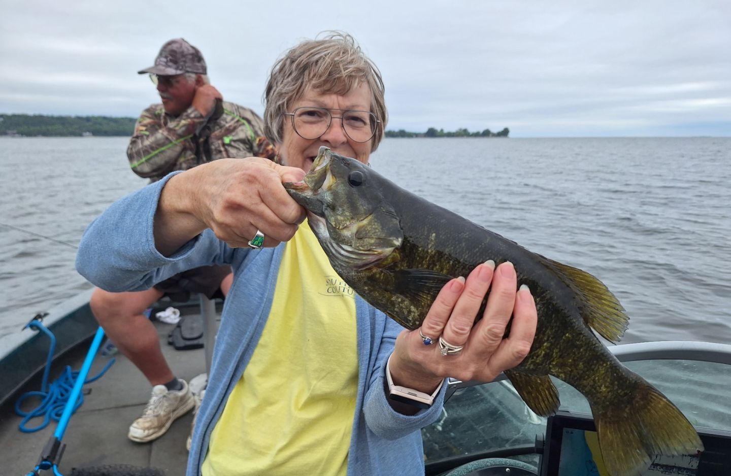 Angler holding freshly caught smallmouth bass on fishing boat