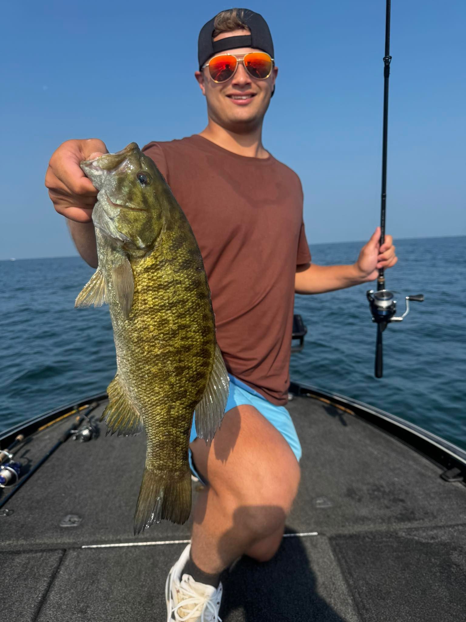 Freshly caught smallmouth bass being displayed on fishing boat deck over open water