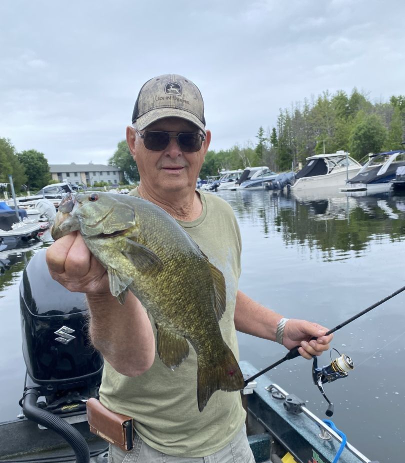 Angler holding freshly caught smallmouth bass on boat at marina
