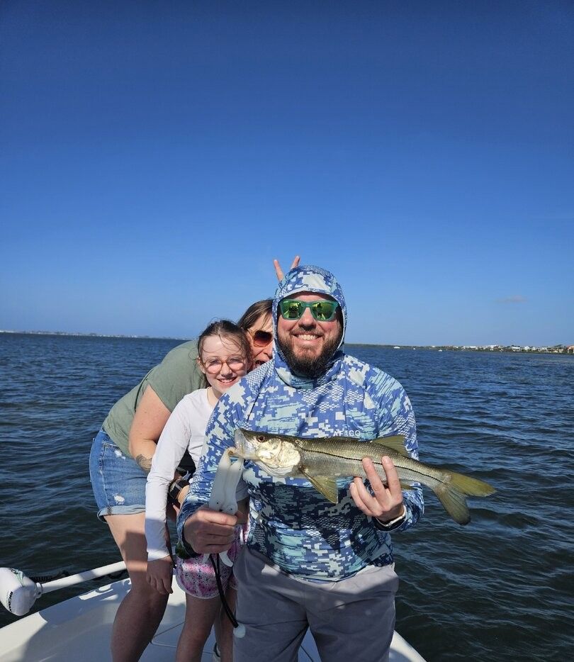 Angler holding freshly caught snook on boat with clear blue sky