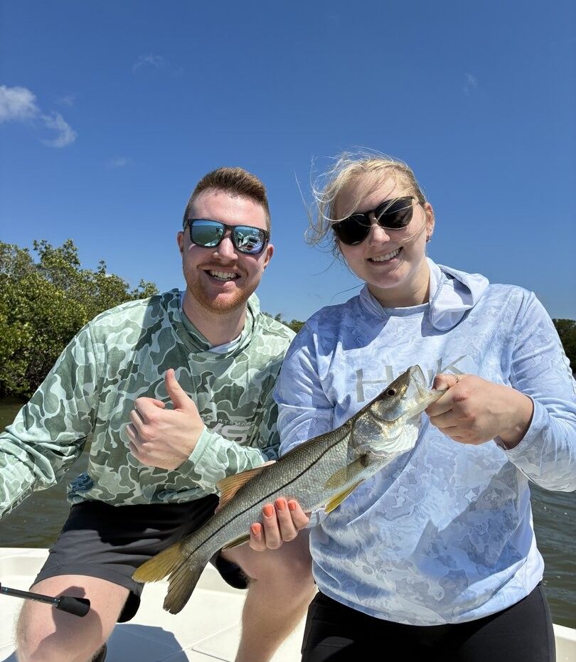 Freshly caught snook being held on fishing boat under clear blue sky