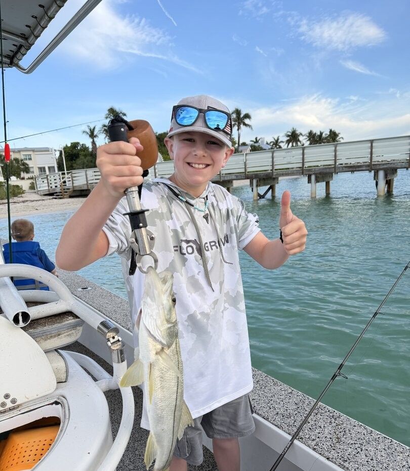 Snook caught while fishing on boat in tropical waters with bridge and palm trees in background