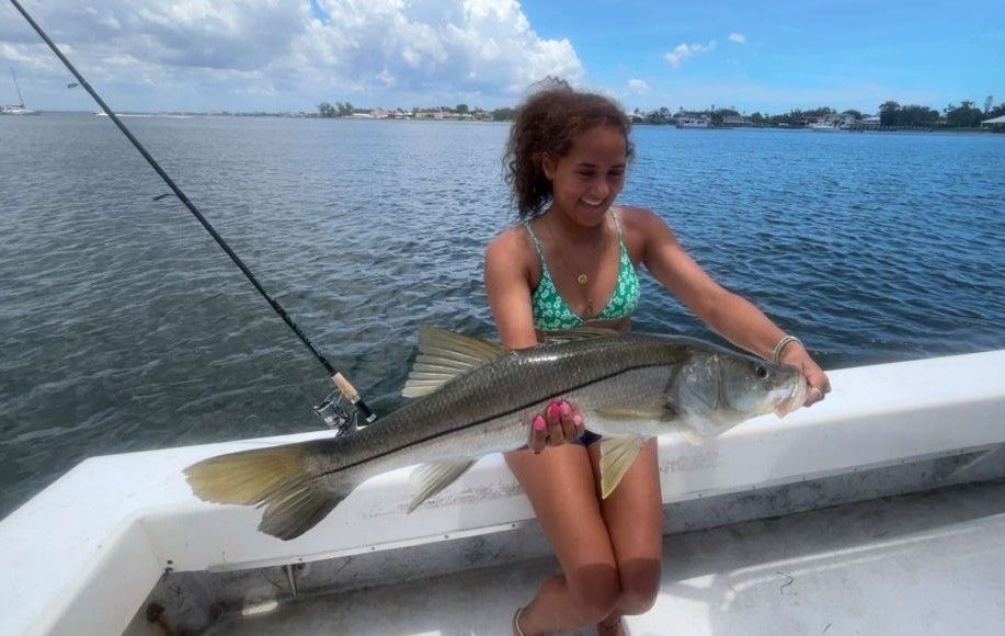 Angler holding caught snook fish on boat deck during fishing trip