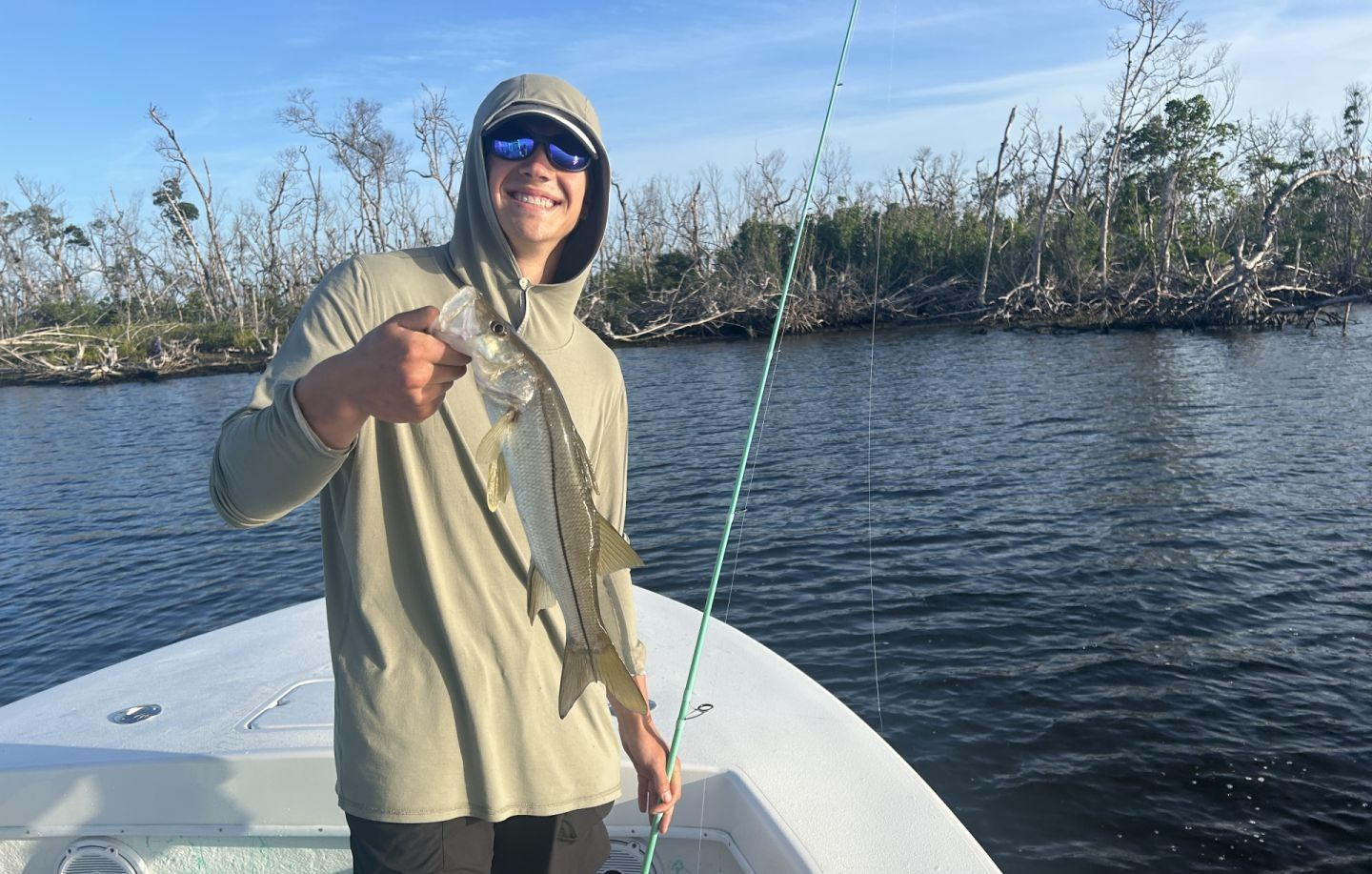 Angler holding a caught snook on a fishing boat
