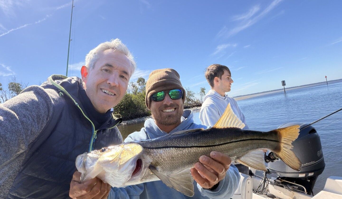 Fresh caught snook displayed on fishing boat with multiple anglers celebrating successful fishing trip