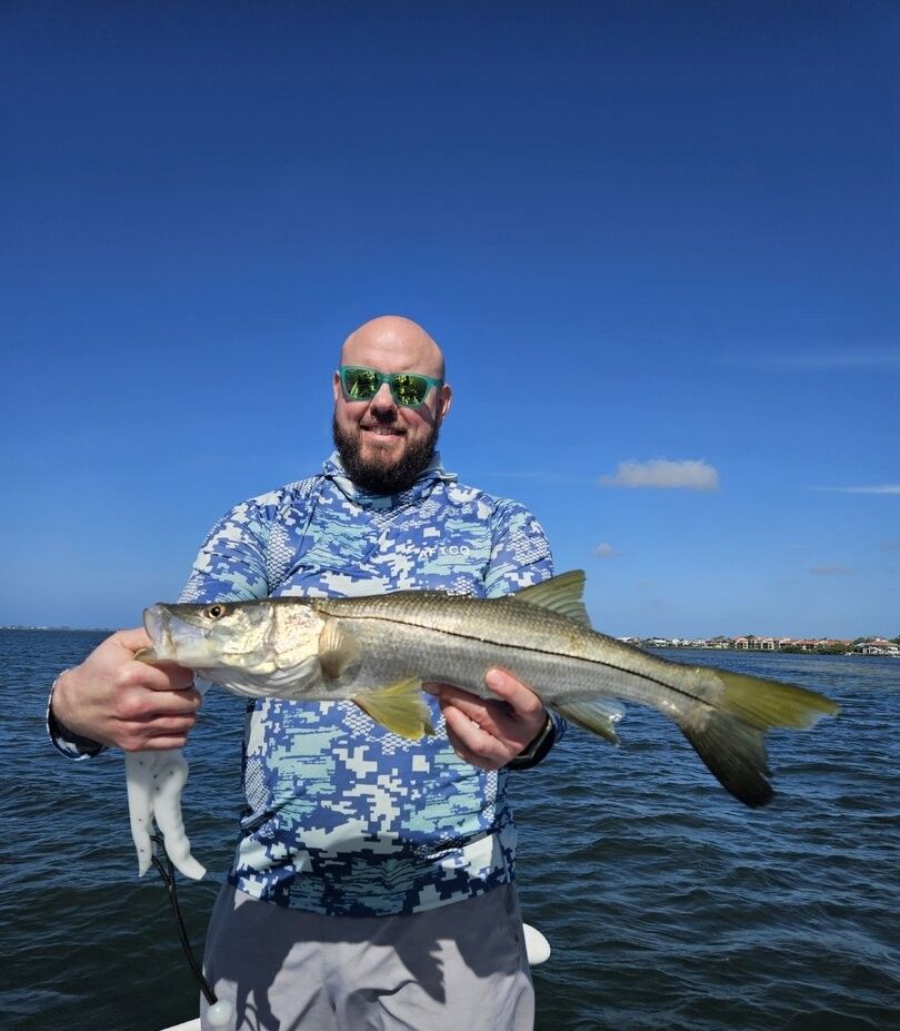 Angler holding freshly caught snook fish on boat in blue ocean waters