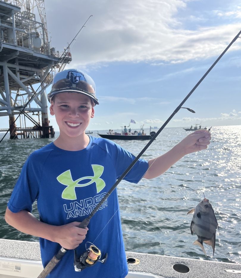 Spadefish caught on fishing line held up near ocean pier