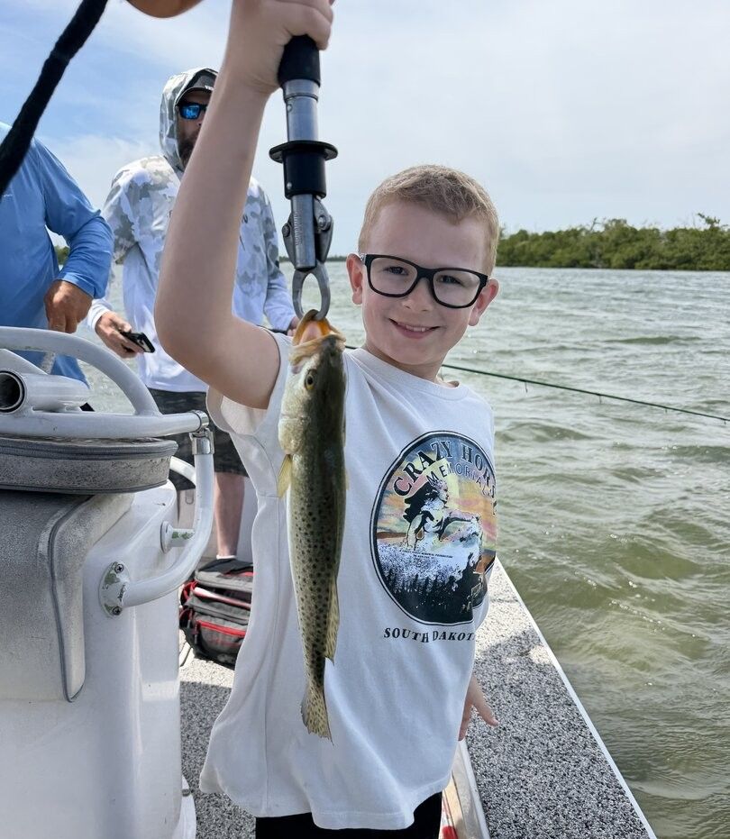 Freshly caught speckled trout being held up on fishing boat