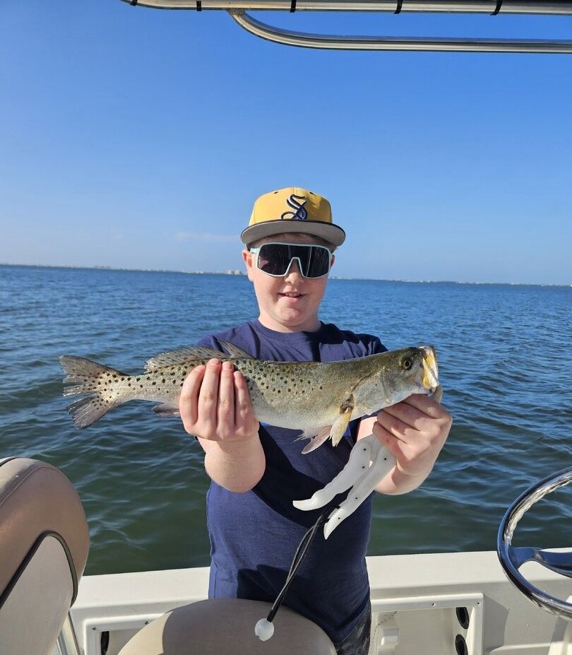 Angler holding a speckled trout on a fishing boat