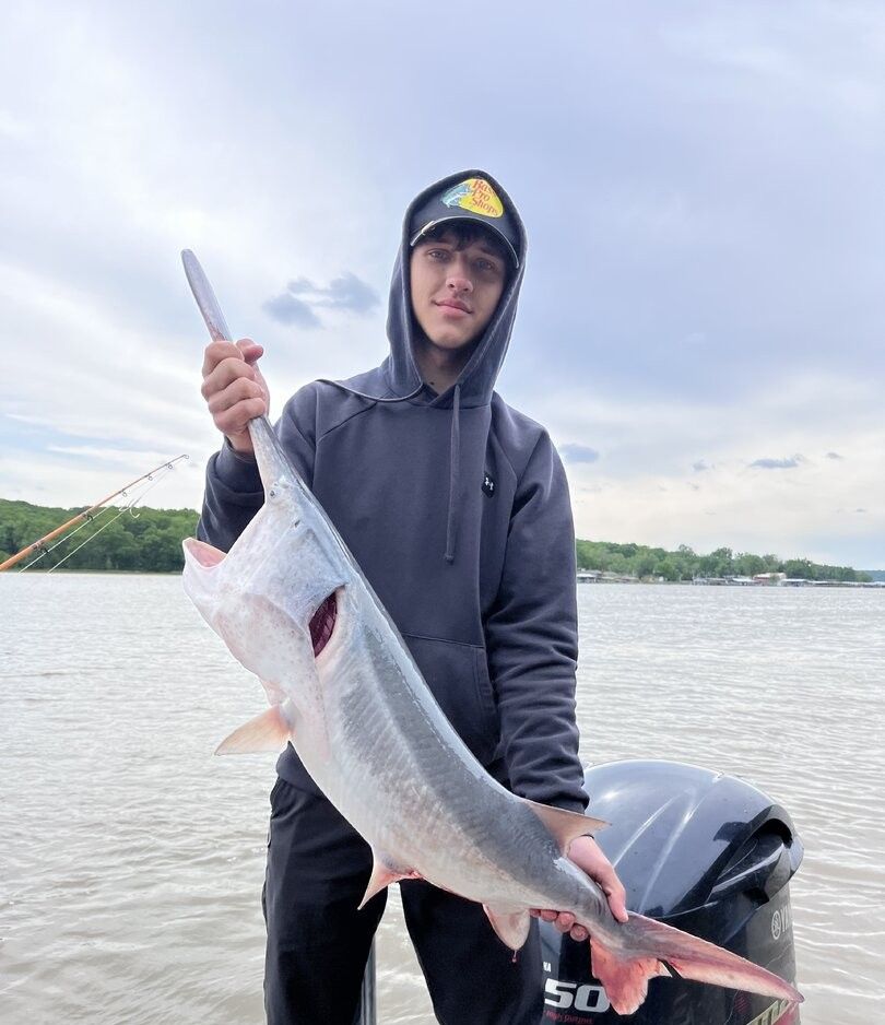 Angler holding freshly caught fish on boat during fishing trip