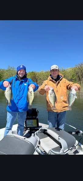 Two anglers displaying four freshly caught fish on boat