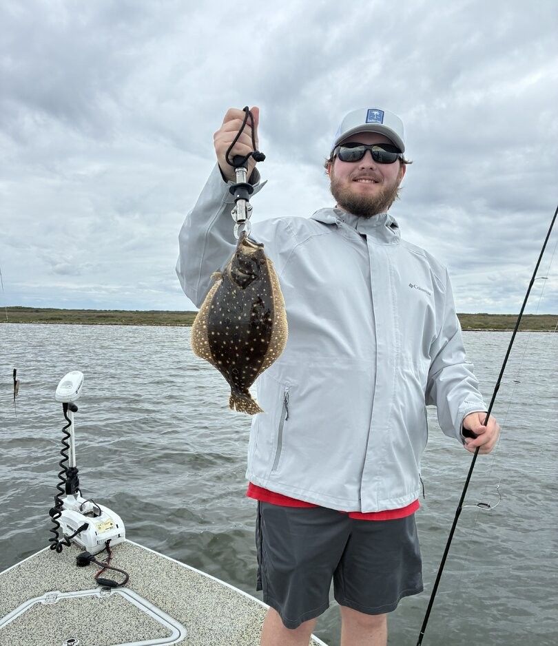 Angler holding freshly caught summer flounder on fishing boat
