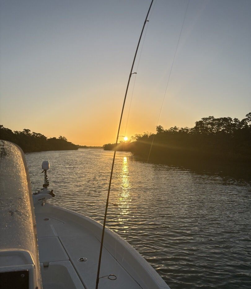 Fishing boat on calm water during sunset with fishing rod extended
