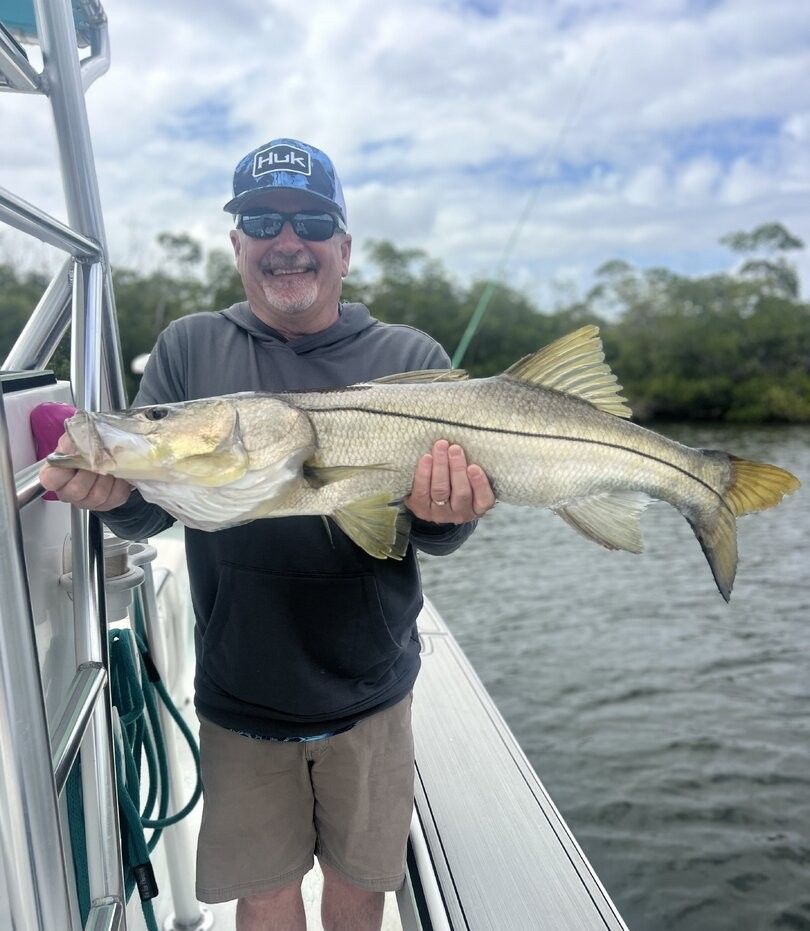 Angler holding large snook fish on boat deck during fishing trip