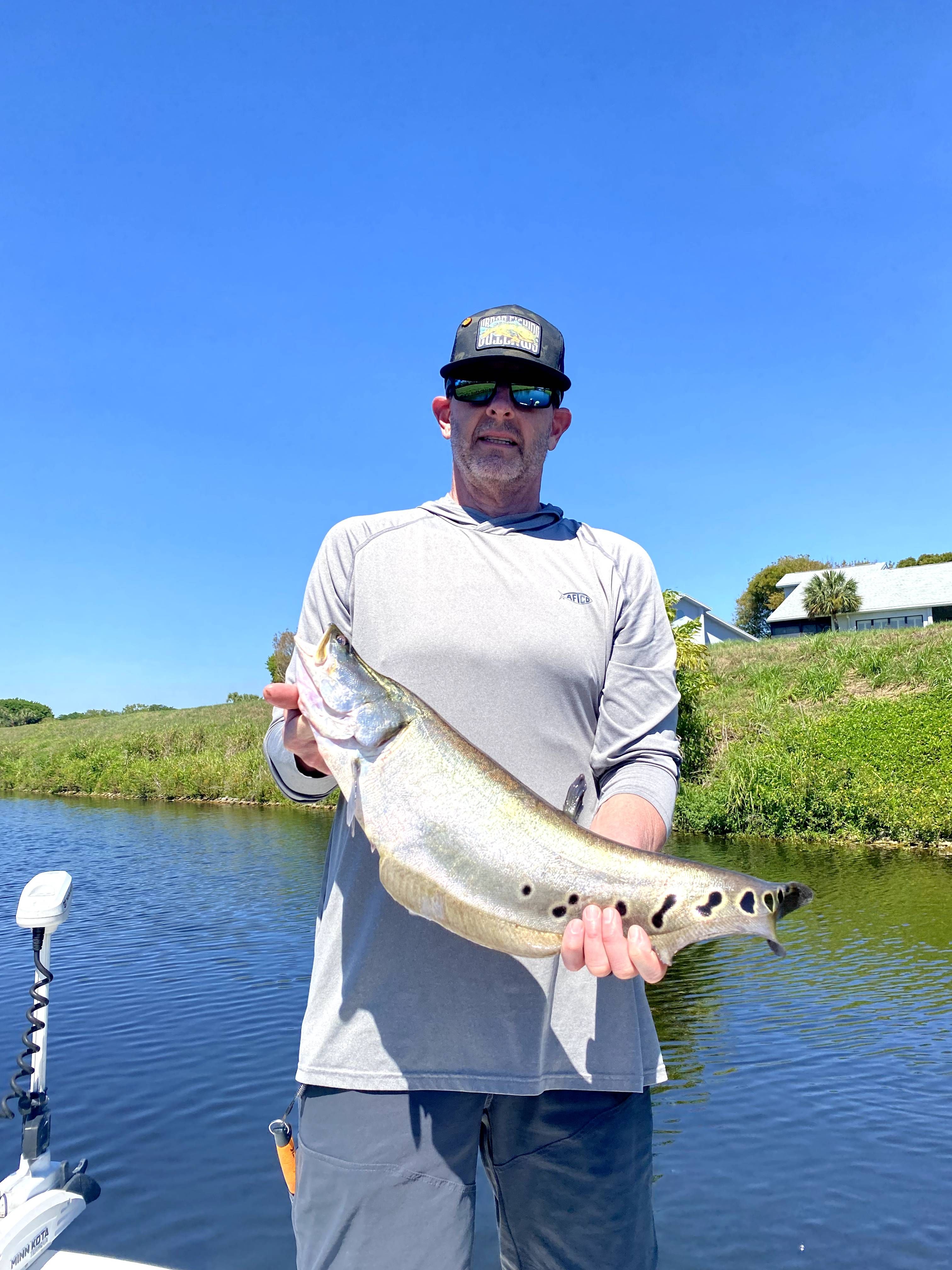 Angler holding large fish on boat in waterway