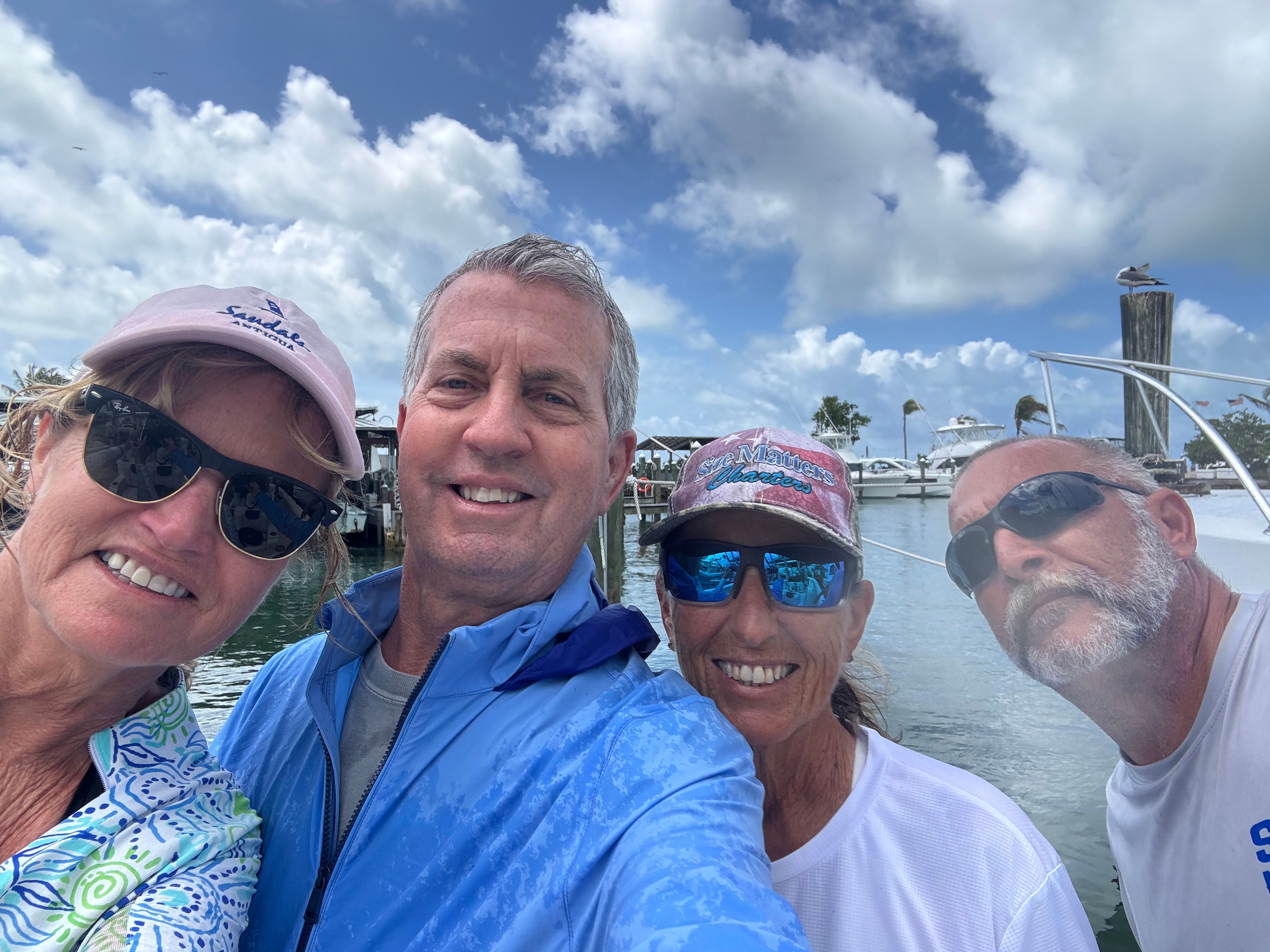 Four people on a boat enjoying a day out on the water with blue sky and clouds in background
