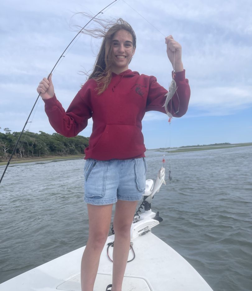 Angler holding fishing rod and caught fish on boat in coastal waters