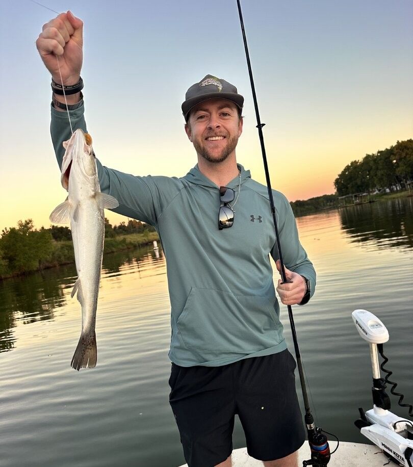 Angler holding caught fish on boat at sunset