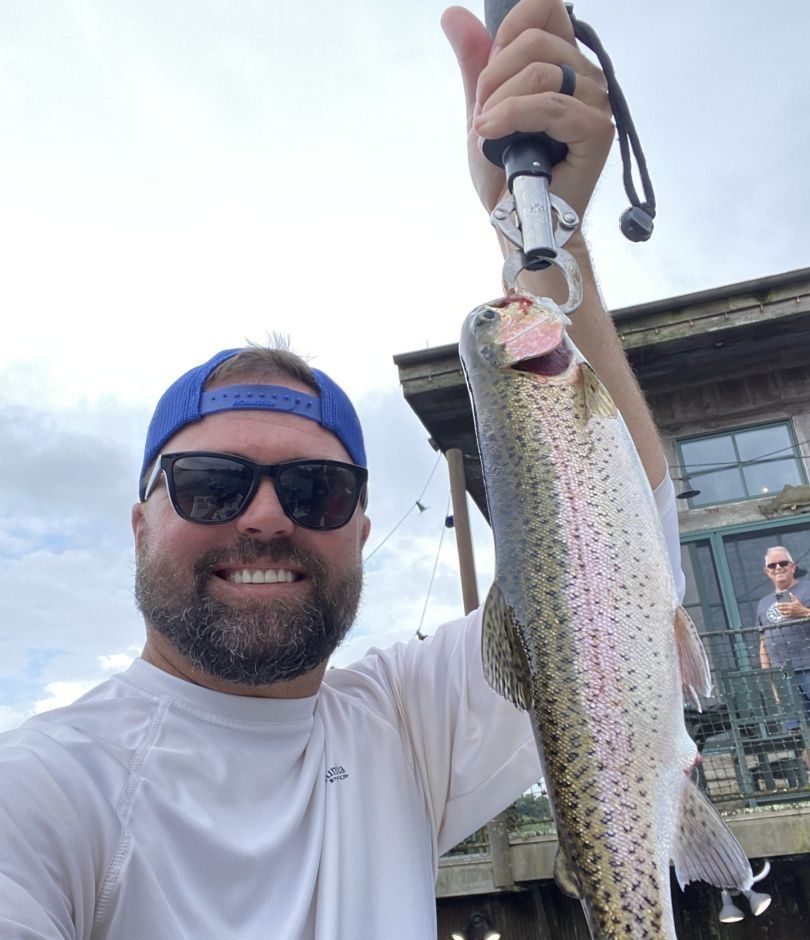 Angler with a rainbow trout catch, fishing in an unknown location