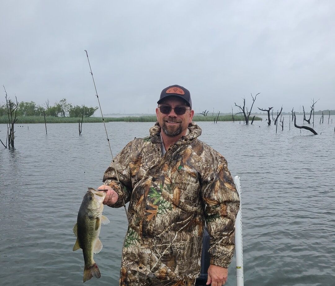Bass fishing catch displayed on boat with dead trees in flooded lake background