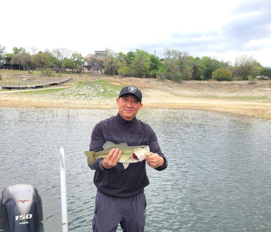 Angler holding freshly caught bass on boat in lake