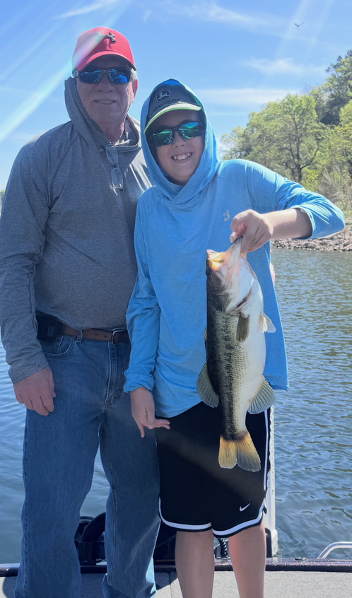 Fishing trip showing caught bass held up for photo on the water