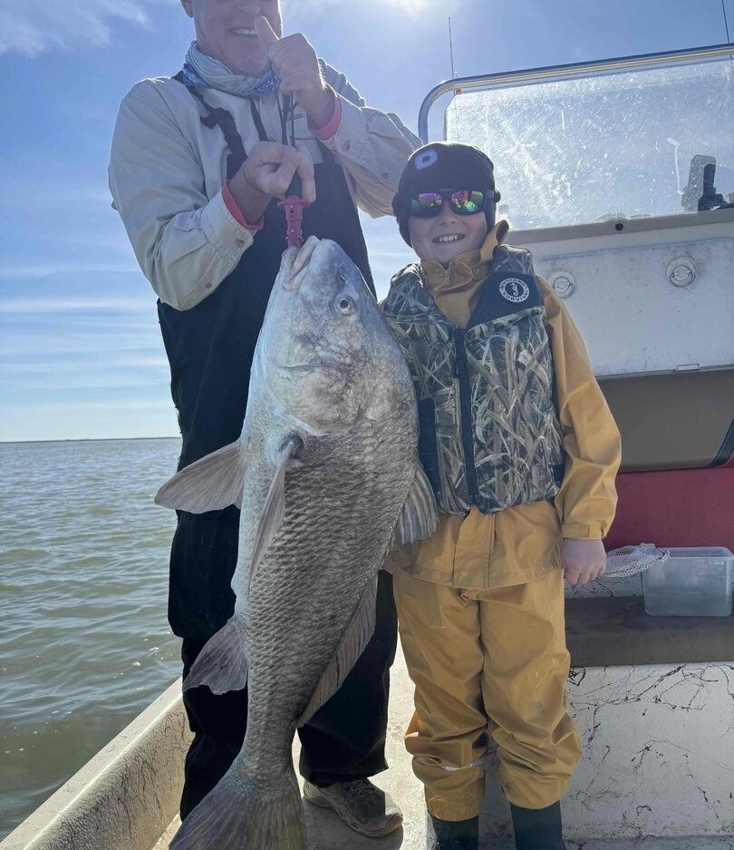 Large black drum fish being held on fishing boat deck