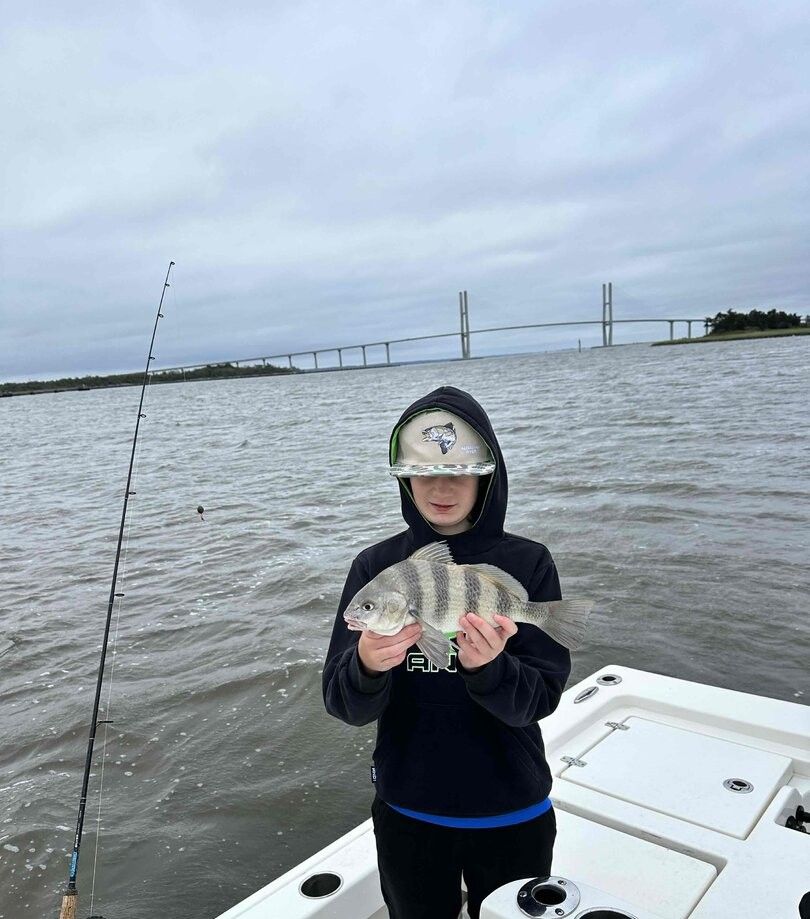 Black drum fish caught while fishing on boat with bridge visible in background