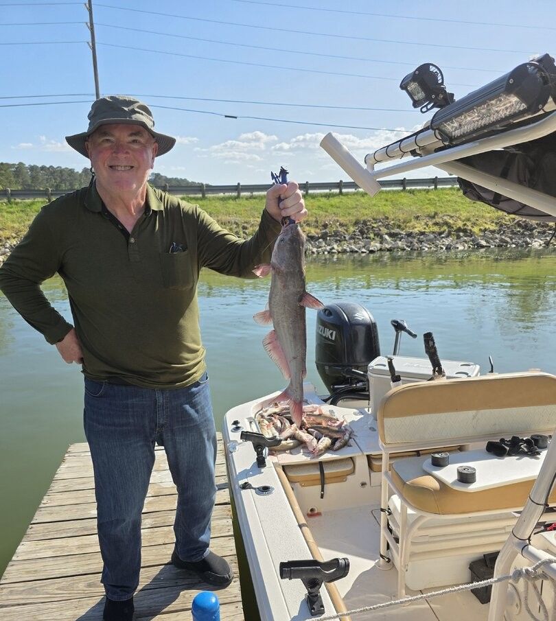 Angler holding freshly caught blue catfish on fishing boat dock