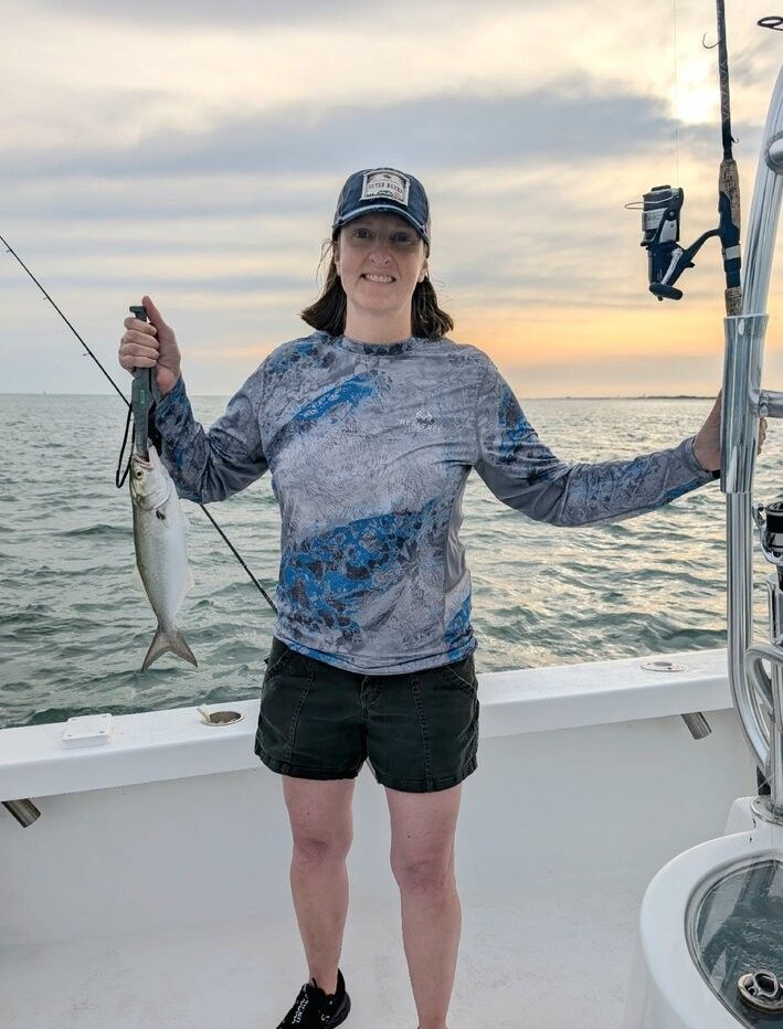 Angler holding freshly caught bluefish on fishing boat deck