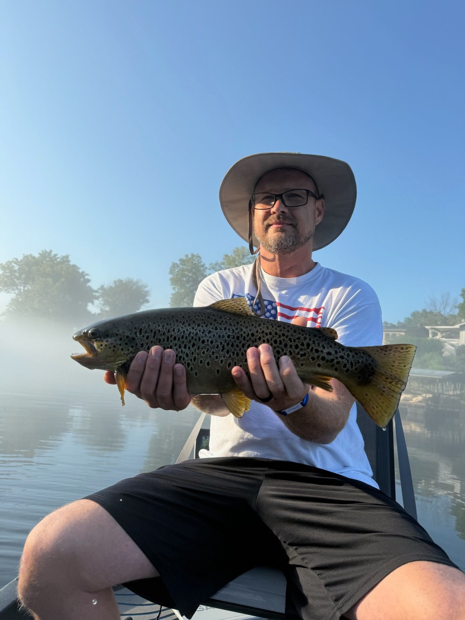 Brown trout caught while fishing on a calm lake with trees in background