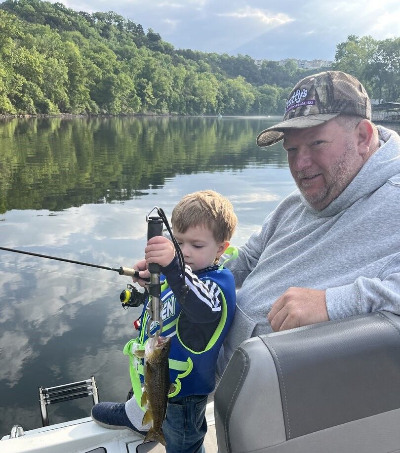 Brown trout caught while fishing on calm lake surrounded by green hills