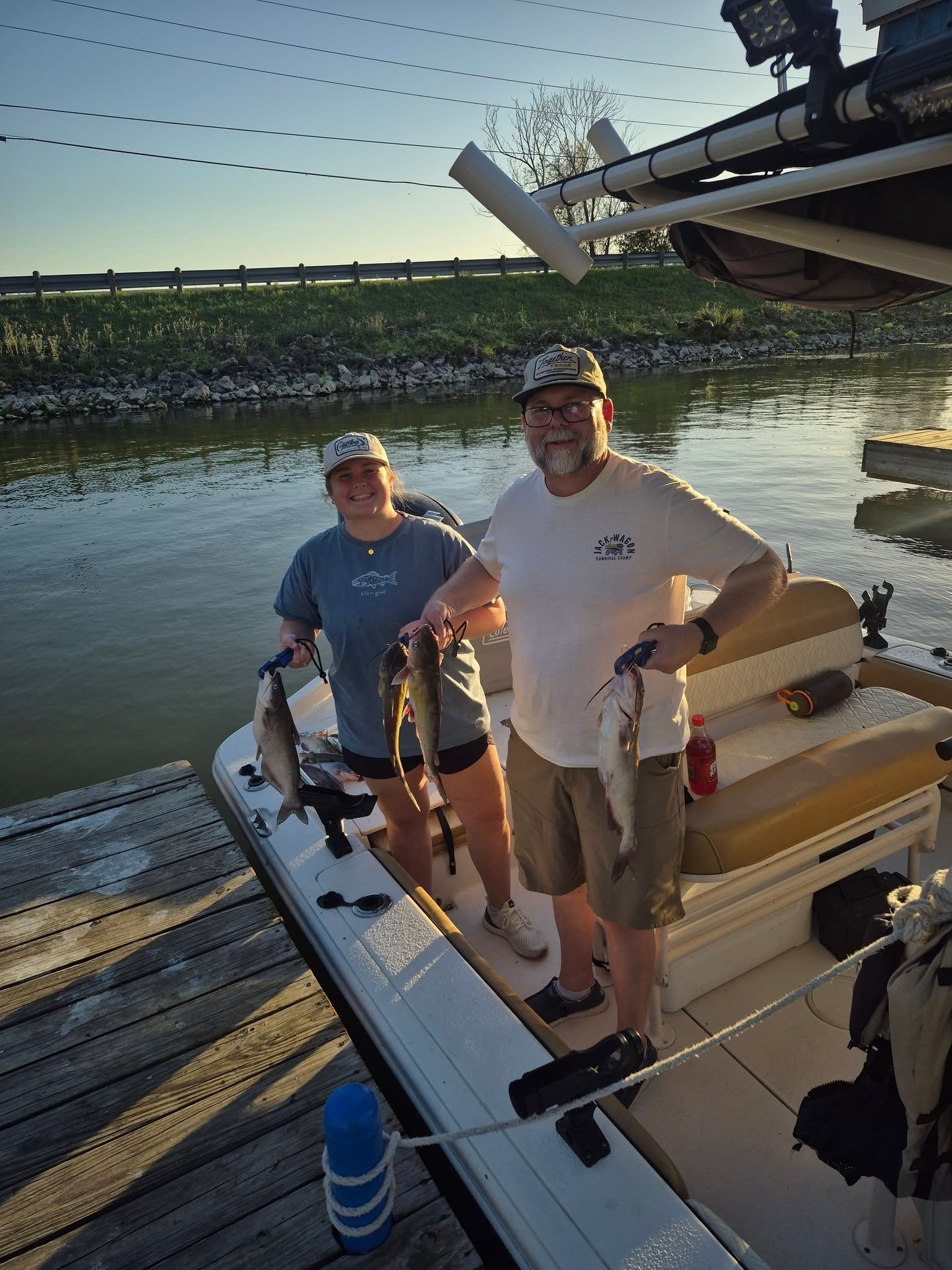 Two anglers on fishing boat displaying caught channel catfish and blue catfish at dock
