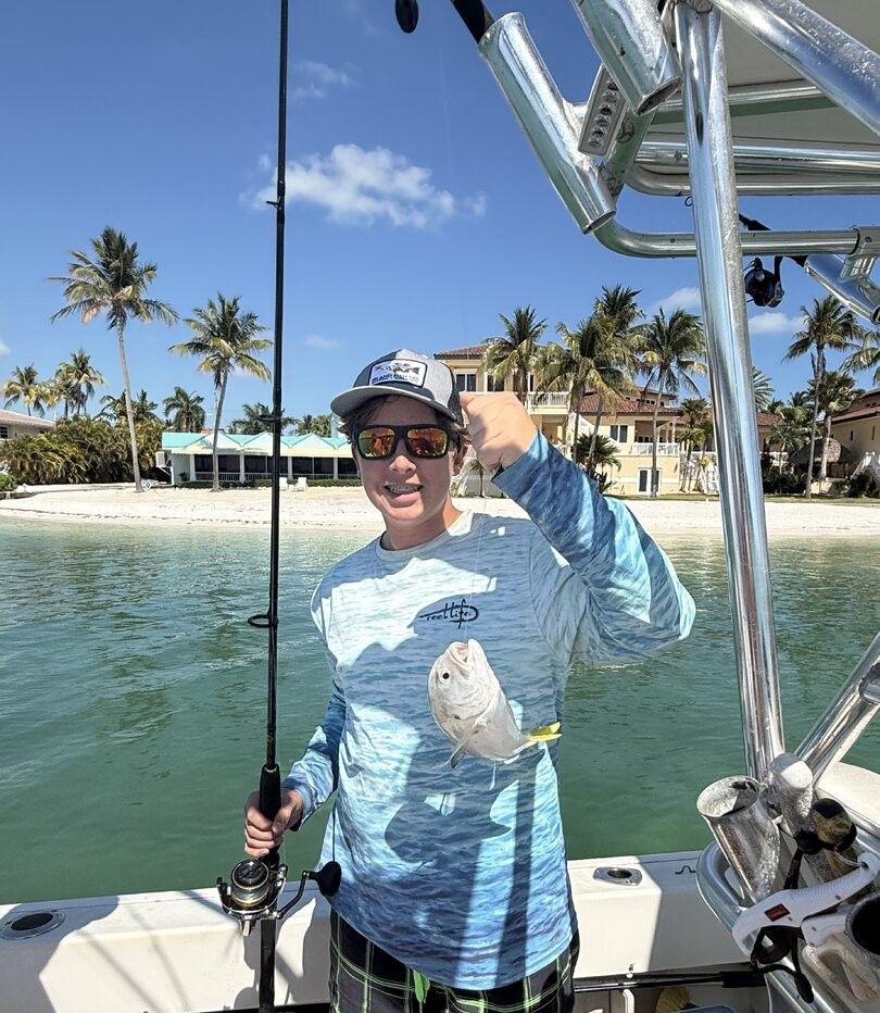 Angler holding freshly caught Crevalle Jack fish on fishing boat in tropical waters
