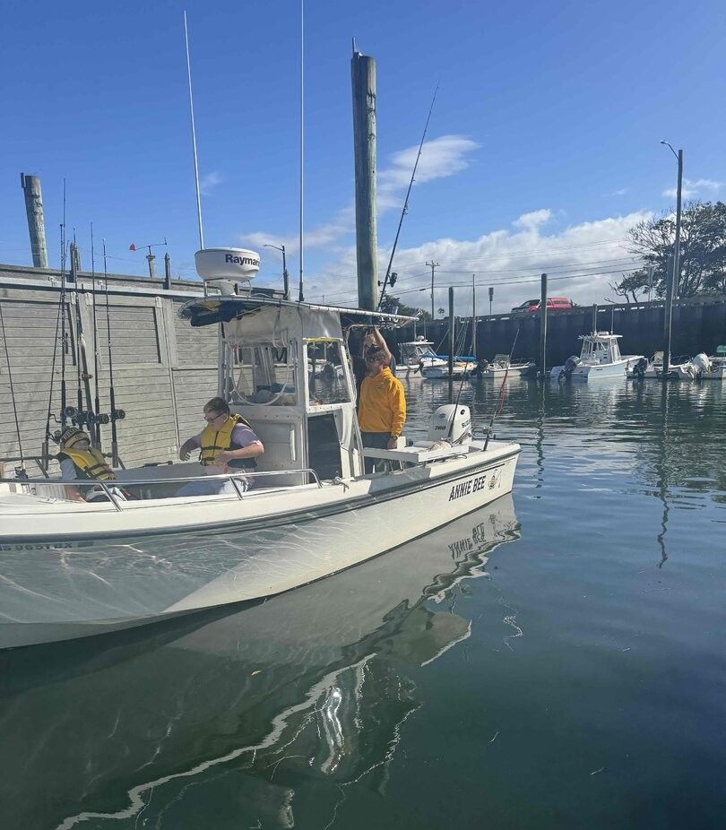 Fishing boat with outriggers and fishing rods docked at marina with other boats in background