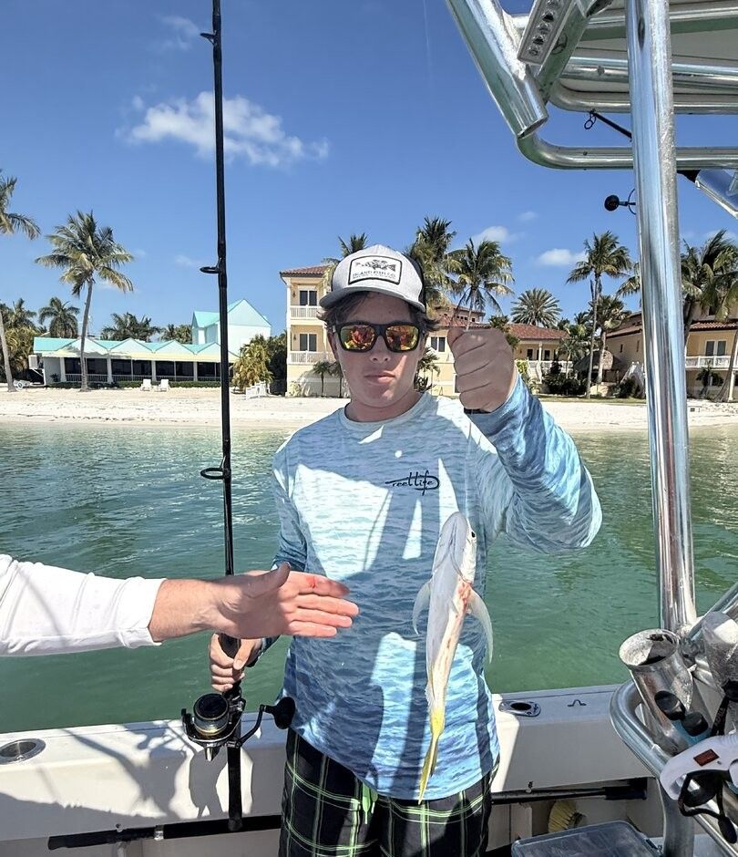 Fishing charter catch showing small fish held up on boat deck