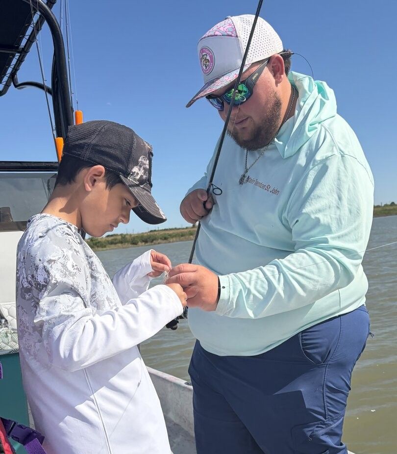 Fishing guide helping young angler with tackle on boat during fishing trip