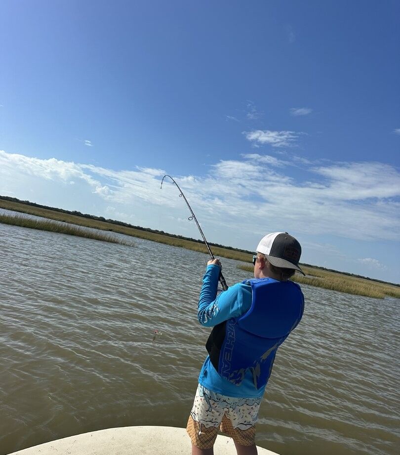 Angler fishing from boat with bent fishing rod indicating fish on the line