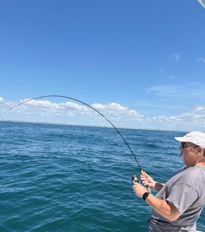 Fishing rod bent with catch over blue ocean water